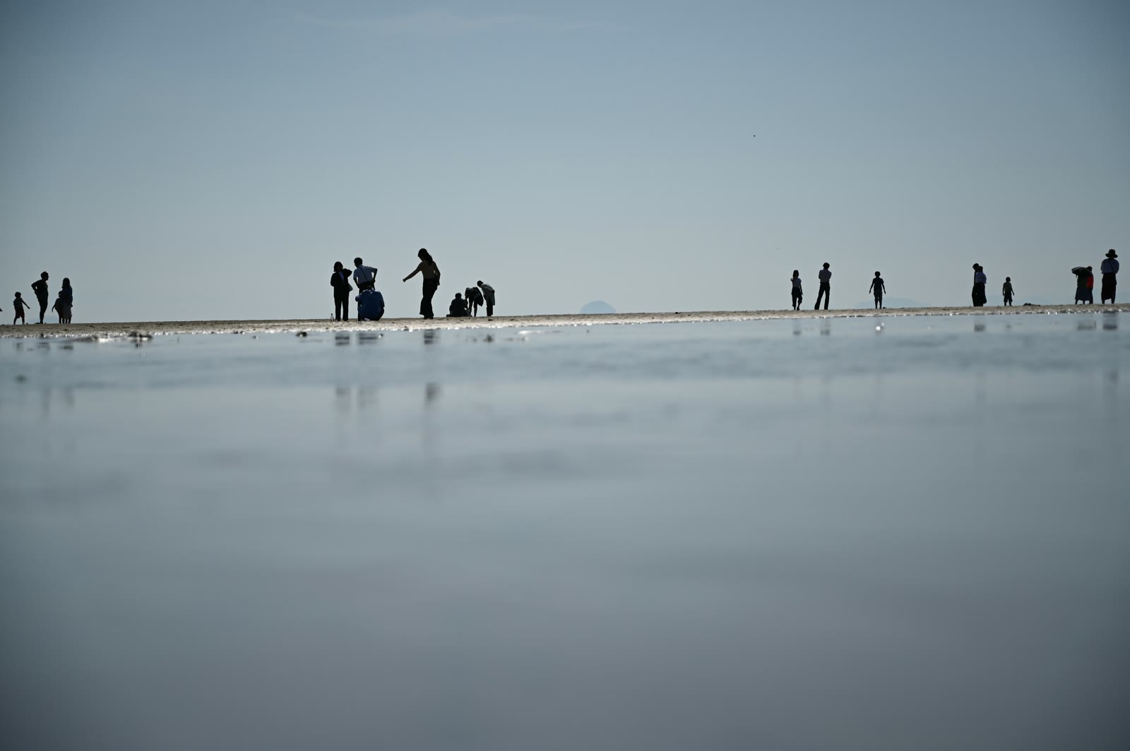 父母ヶ浜の水面に映る人々のシルエット