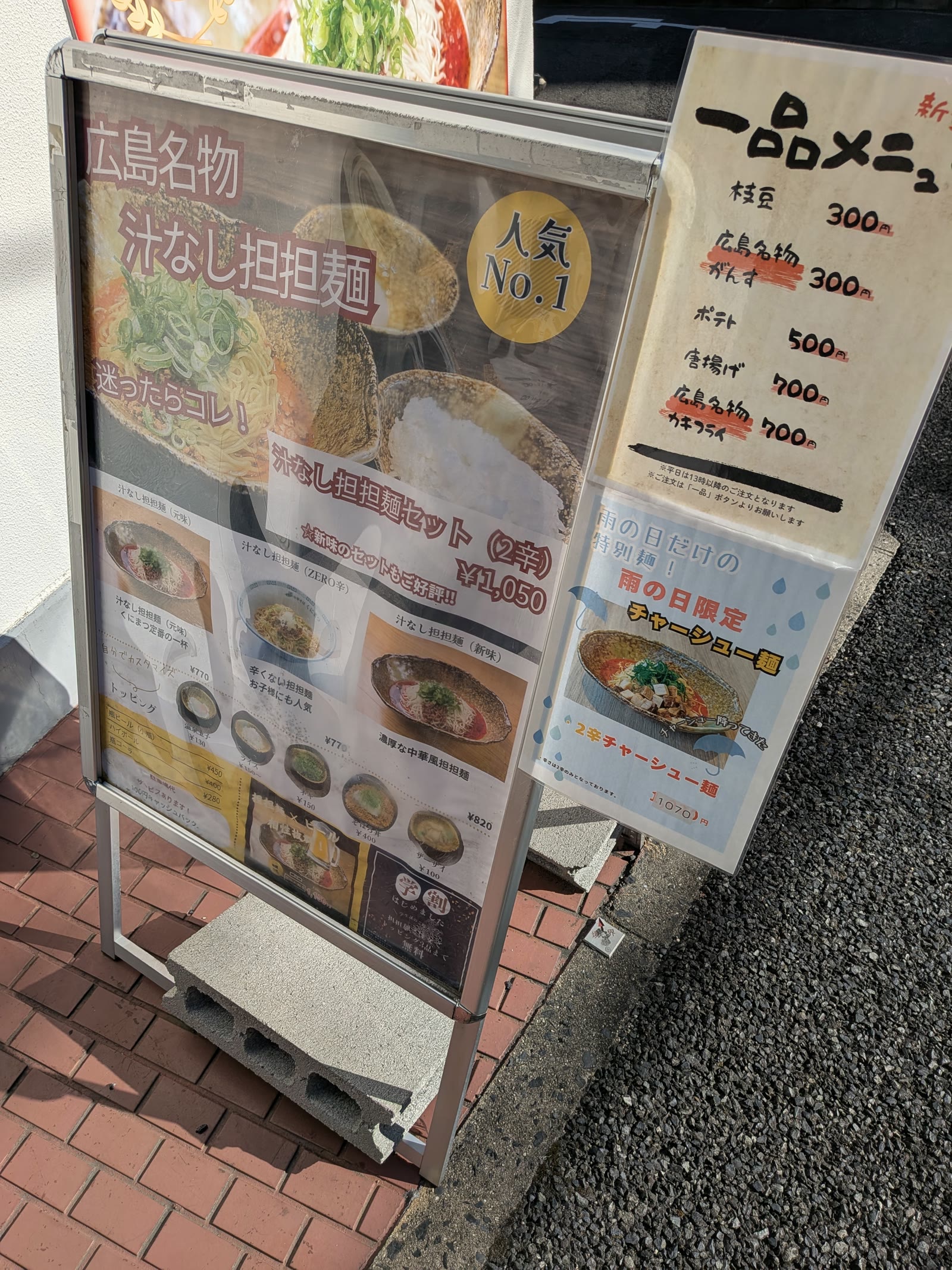 くにまつの店の前のメニュー看板。汁なし担担麺セットと一品メニュー