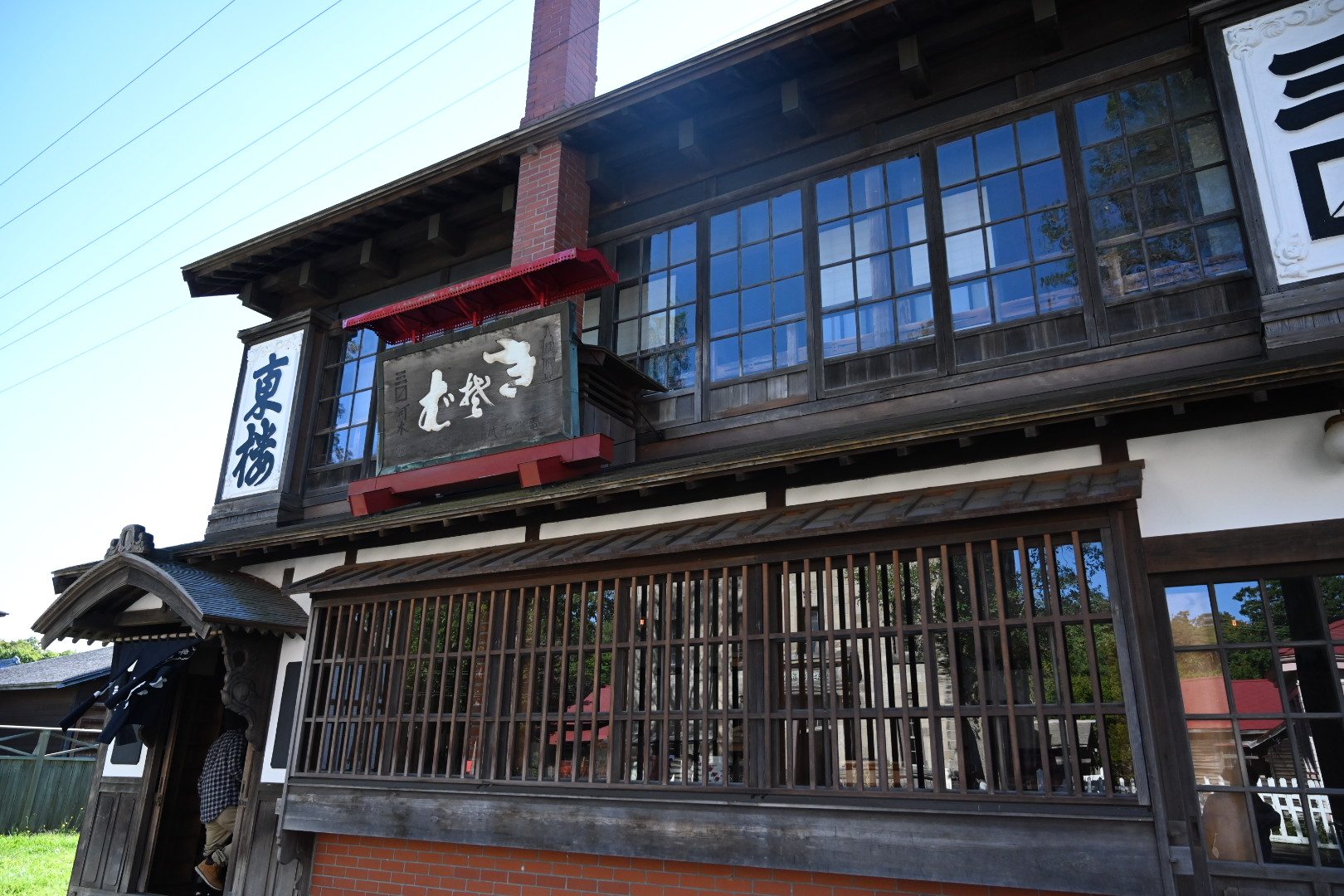 北海道開拓の村の旧三〼河本そば屋。そばの看板と格子窓、レンガの煙突