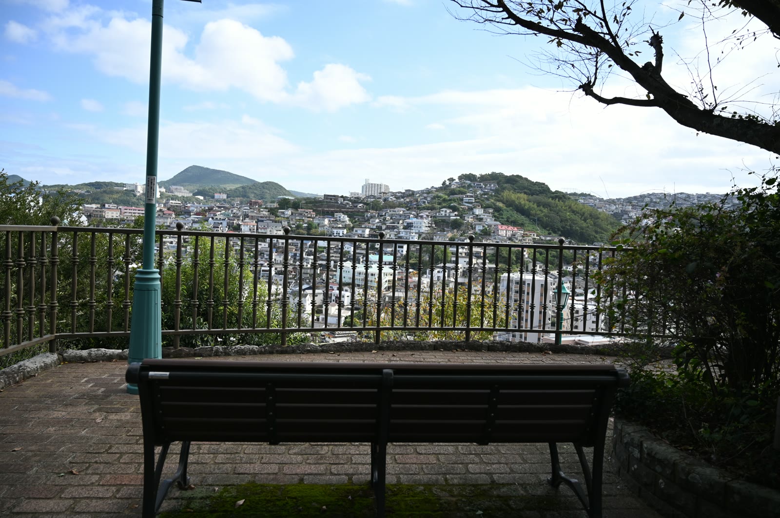南山手の高台のベンチと、手すりの向こうに広がる長崎の町と山