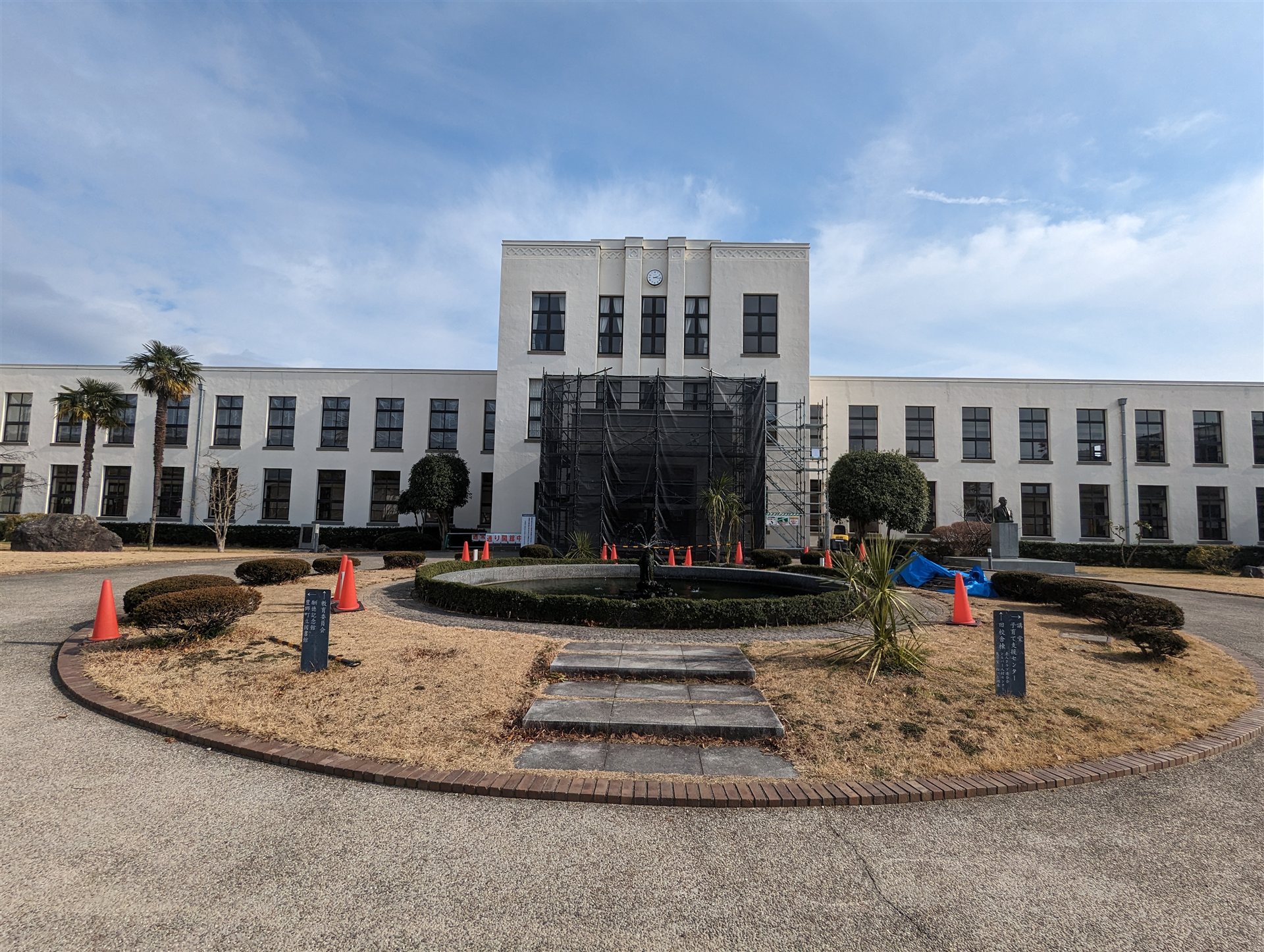 豊郷小学校旧校舎群の正面と円形の花壇(2024年2月、玄関に工事の足場がある)