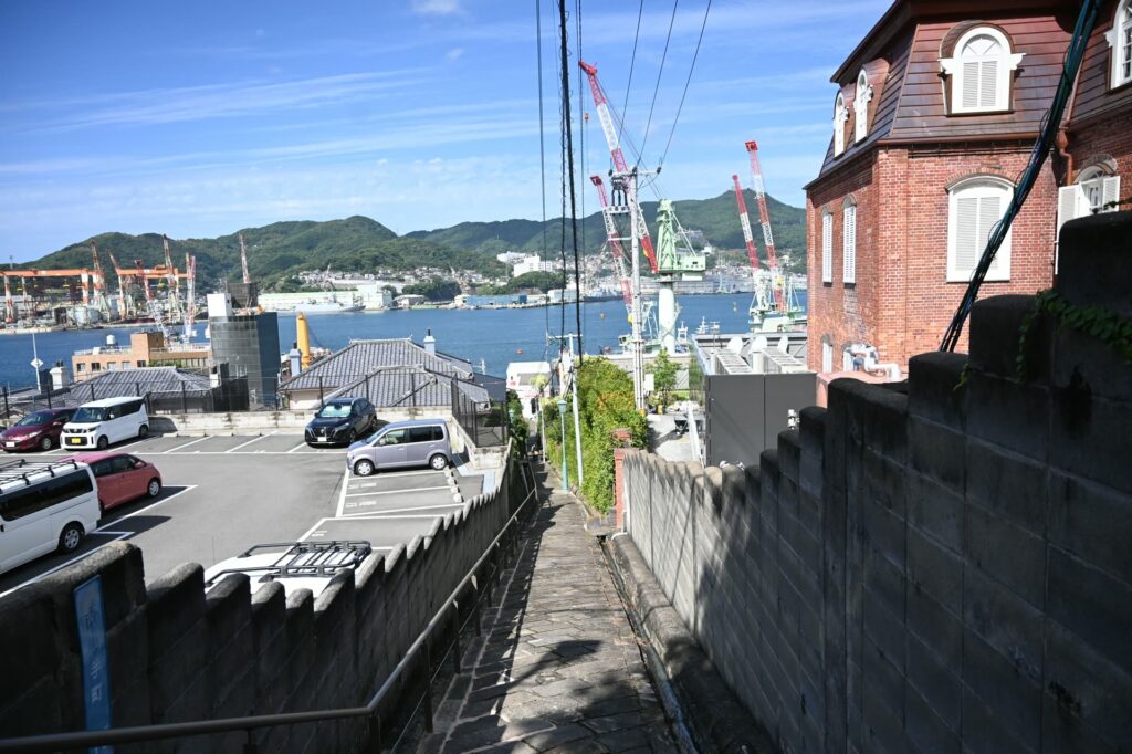 南山手の階段坂から見た旧マリア園の赤レンガの建物と、長崎港の造船所のクレーン