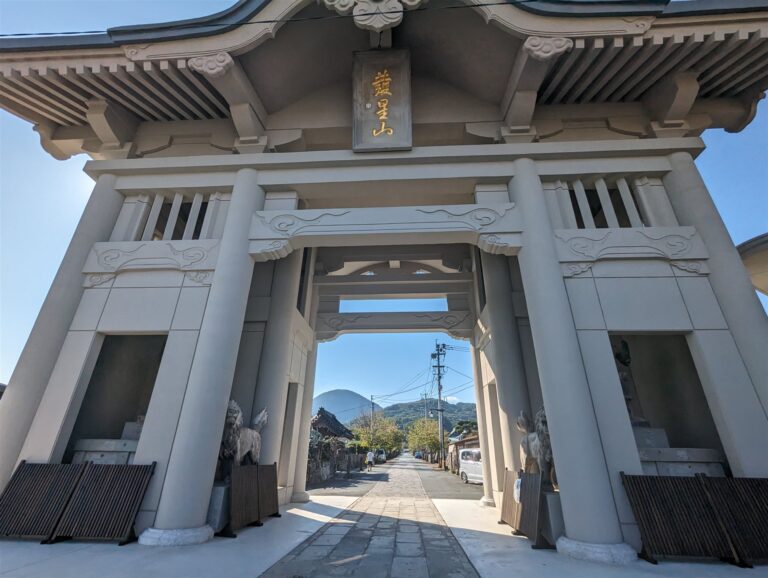 本妙寺の白い仁王門。「發星山」の額がかかり、門の先に石畳の参道と山が見える（熊本市西区）