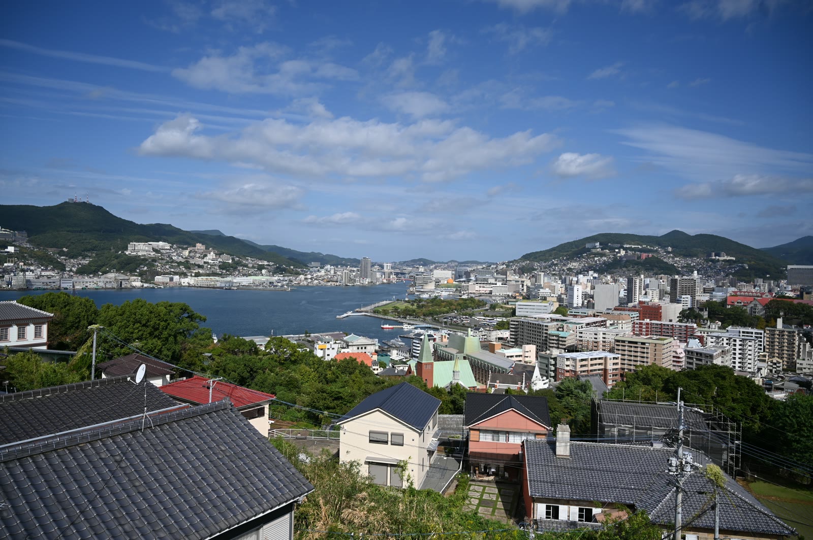 南山手の瓦屋根越しに見た長崎港と市街、青空