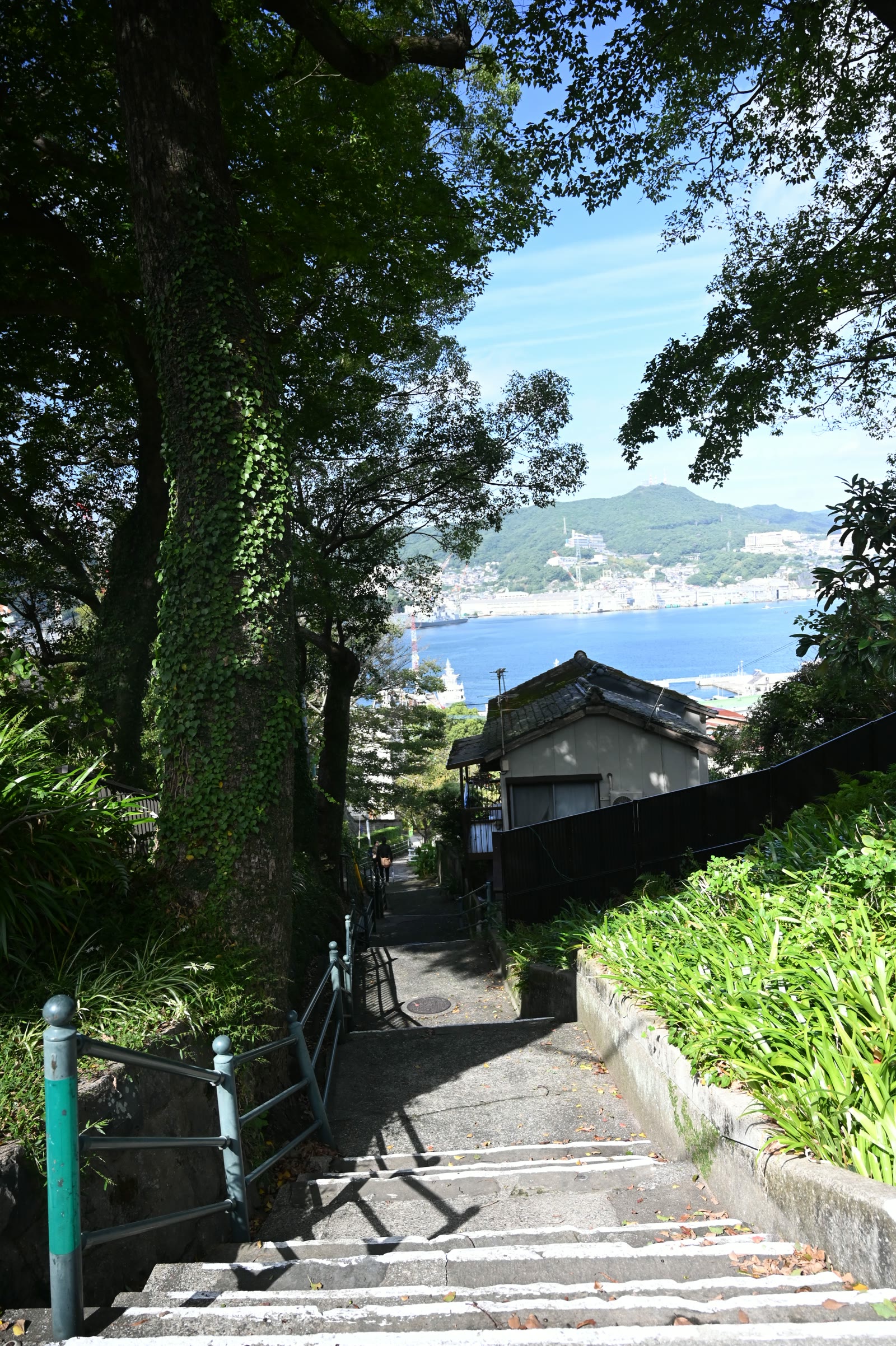 木陰の階段坂と、その先に見える長崎港