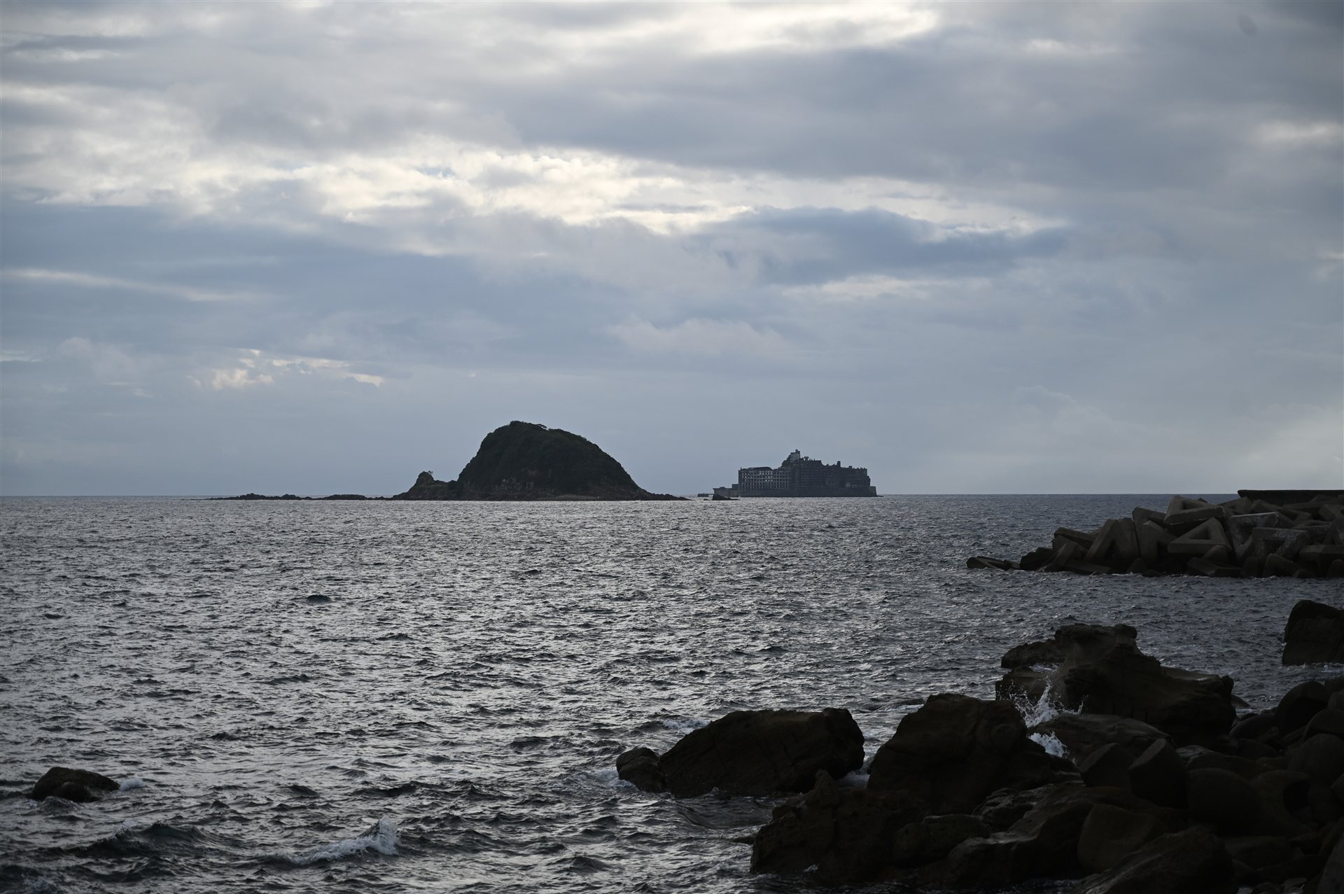 長崎・高島の岩場から見た中ノ島と、建物の並ぶ軍艦島(端島)のシルエット
