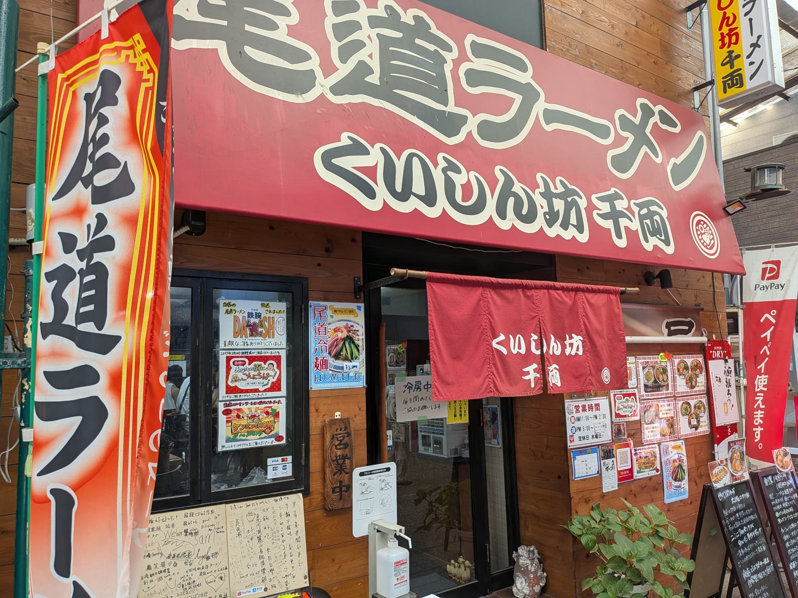 尾道ラーメン くいしん坊 千両の外観。赤い看板とのれん