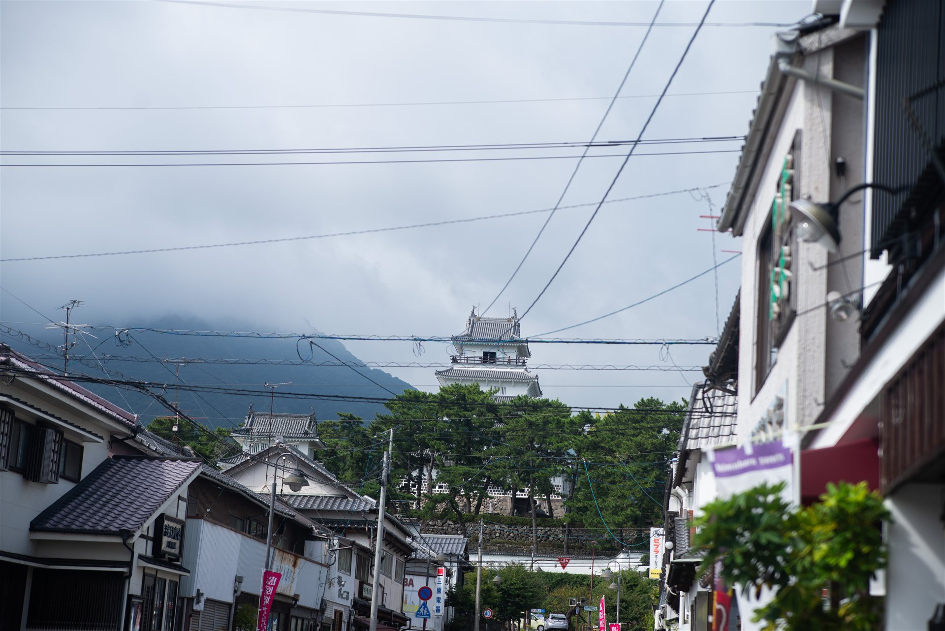 島原の商店街の先に見える島原城の天守と、雲のかかった眉山