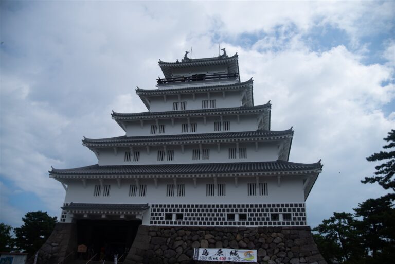 島原城の五層の天守を下から見上げた様子。石垣の前に築城400年の幕